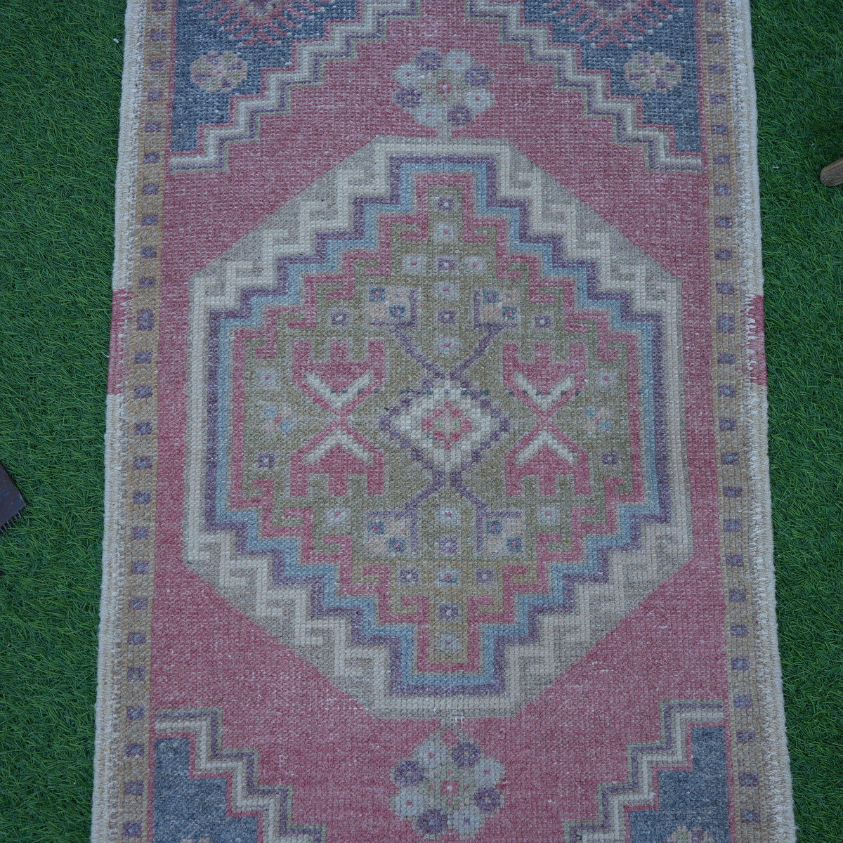 Close-up of the red Turkish small vintage rug showing traditional details, hand-knotted weave, wool and cotton and low pile.