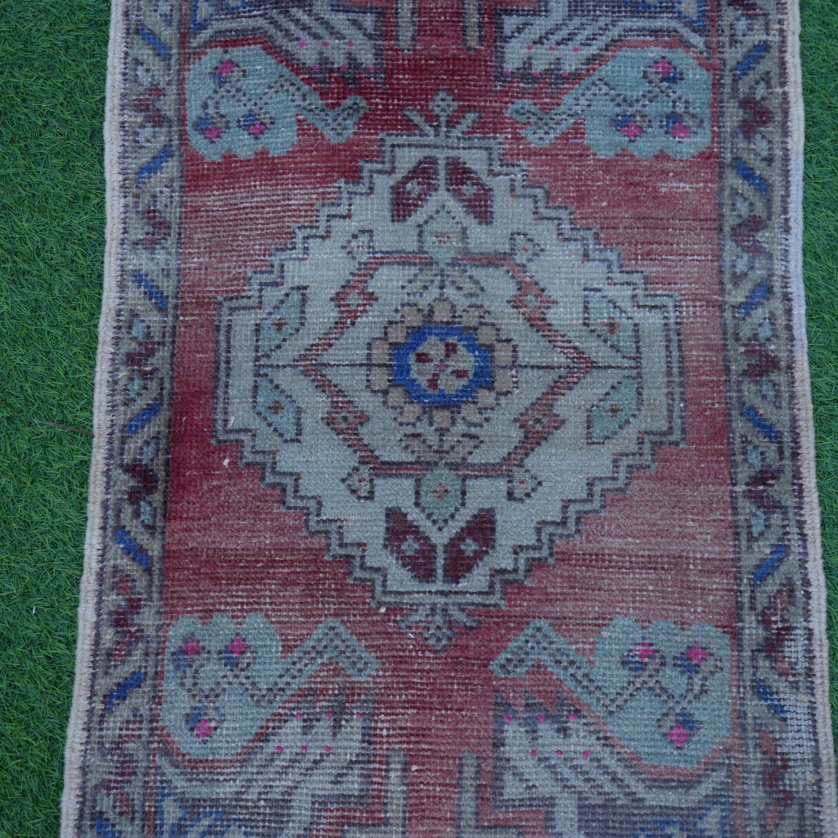 Close-up of the red Turkish small vintage rug showing traditional details, hand-knotted weave, wool and cotton and low pile.
