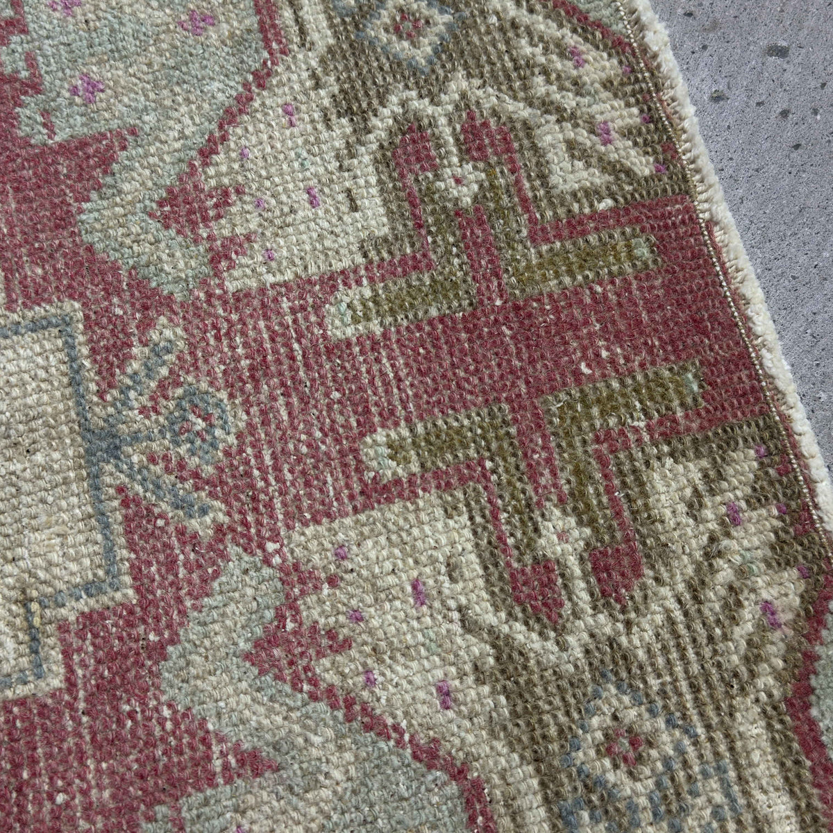 Close-up of the red Turkish small vintage rug showing traditional details, hand-knotted weave, wool and cotton and low pile.