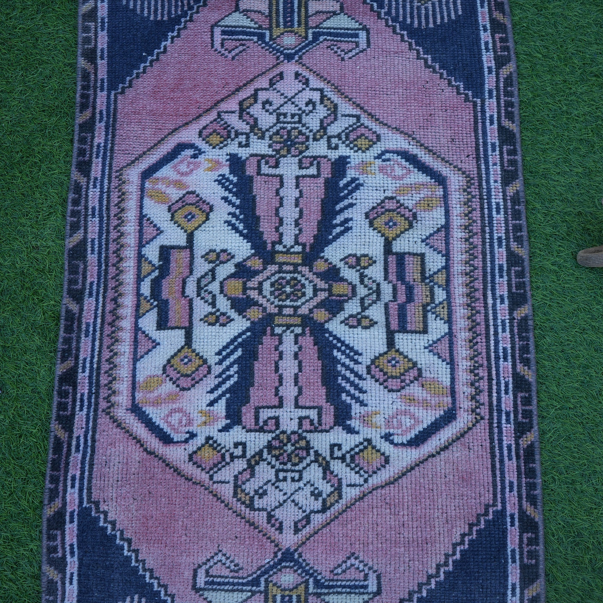 Close-up of the pink Turkish small vintage rug showing traditional details, hand-knotted weave, wool and cotton and low pile.