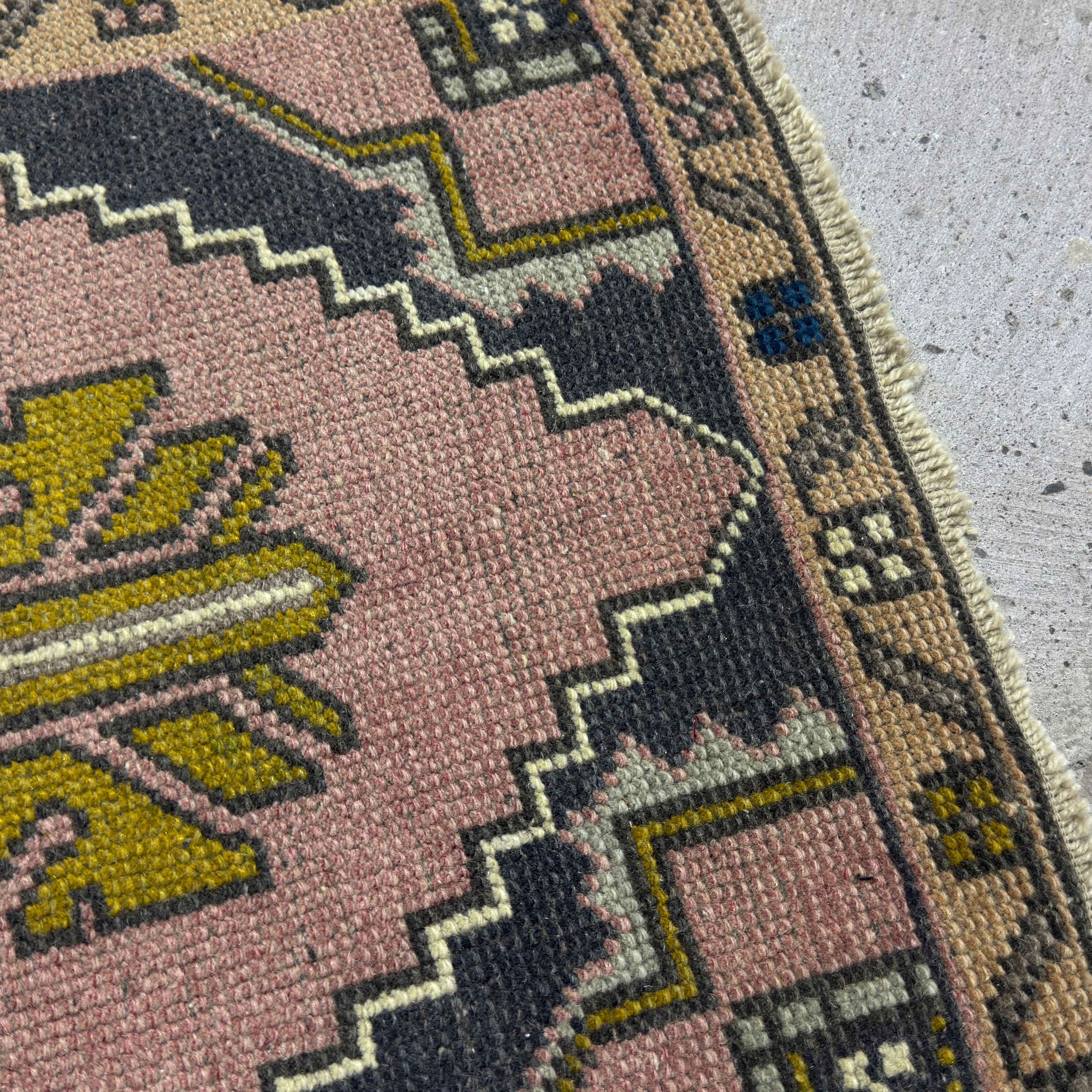 Close-up of the pink Turkish small vintage rug showing traditional details, hand-knotted weave, wool and cotton and low pile.