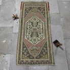 Pink 2' x 4' Turkish small vintage rug in wool and cotton, shown on the floor.