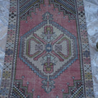 Close-up of the pale red Turkish small vintage rug showing traditional details, hand-knotted weave, wool and cotton and low pile.