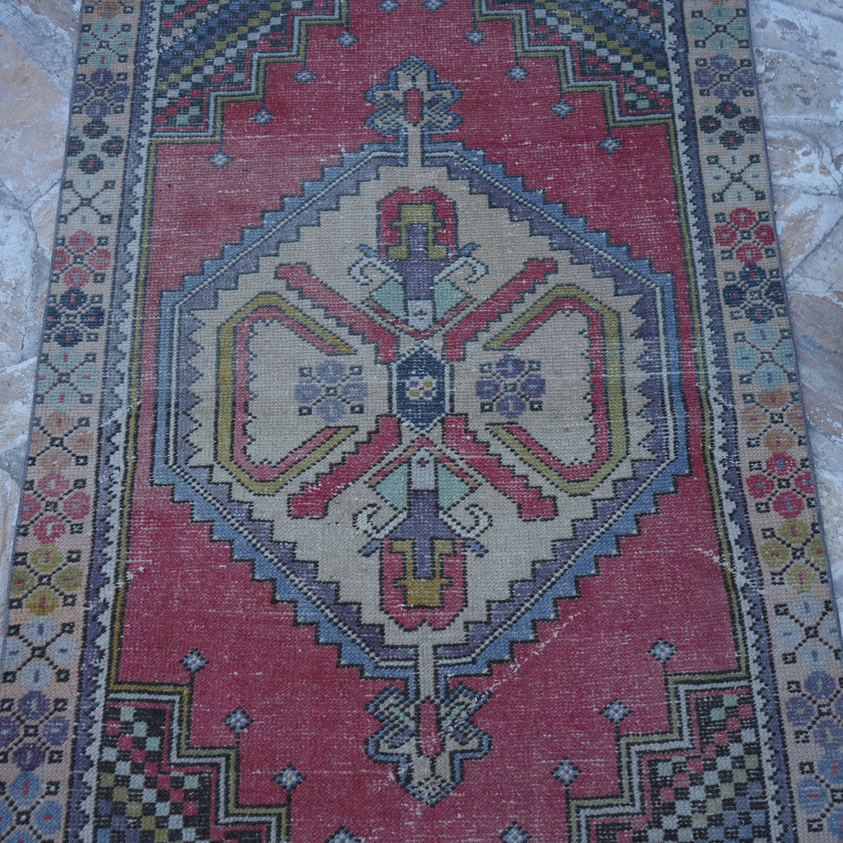 Close-up of the red Turkish small vintage rug showing traditional details, hand-knotted weave, wool and cotton and low pile.