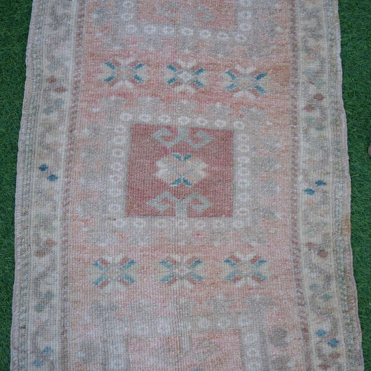 Close-up of the pale orange Turkish small wool rug showing neutral details, hand-knotted weave, wool and low pile.