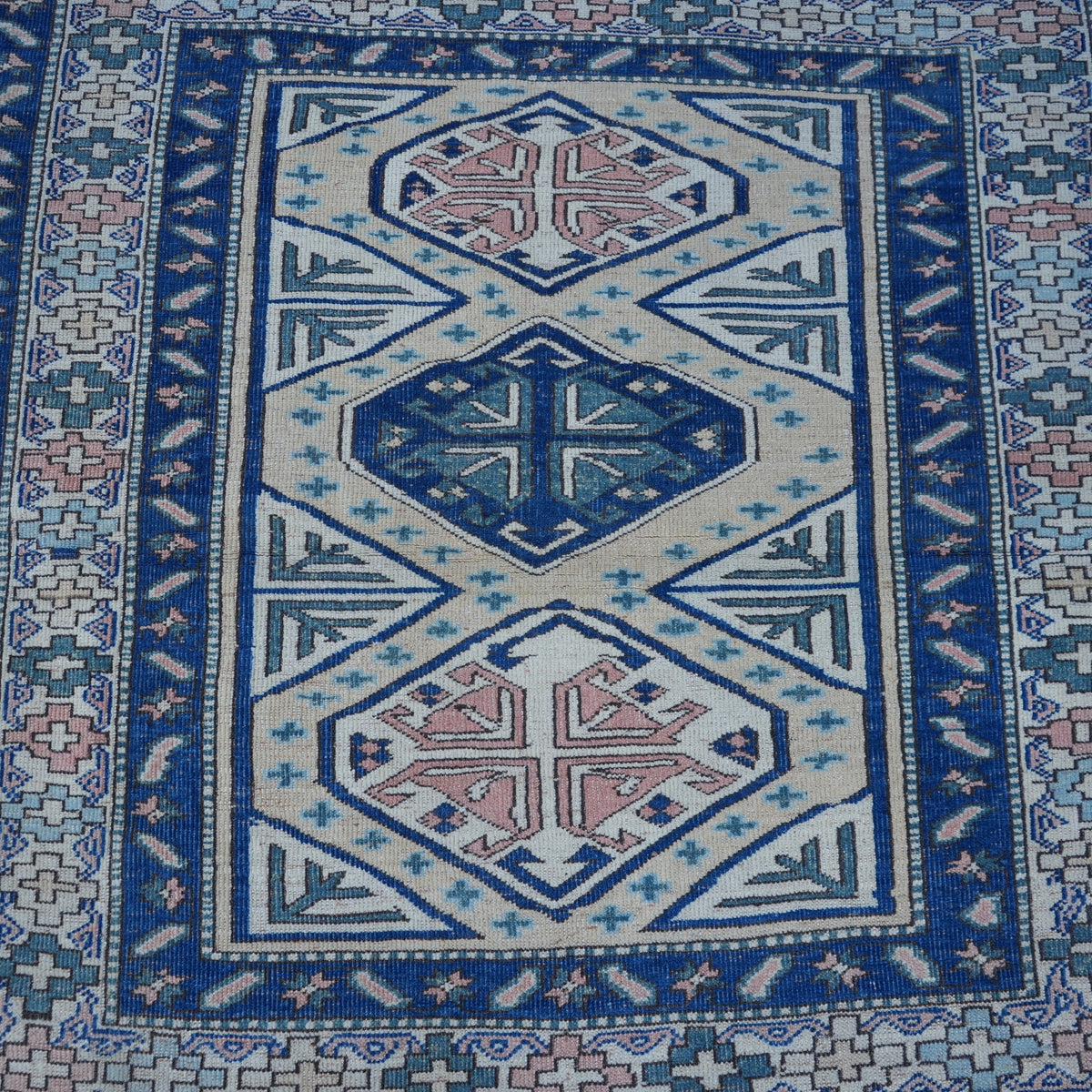Close-up of the red Turkish square vintage rug, hand-knotted weave, wool and low pile.