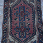 Close-up of the red Turkish traditional vintage rug showing traditional details, hand-knotted weave, wool and low pile.