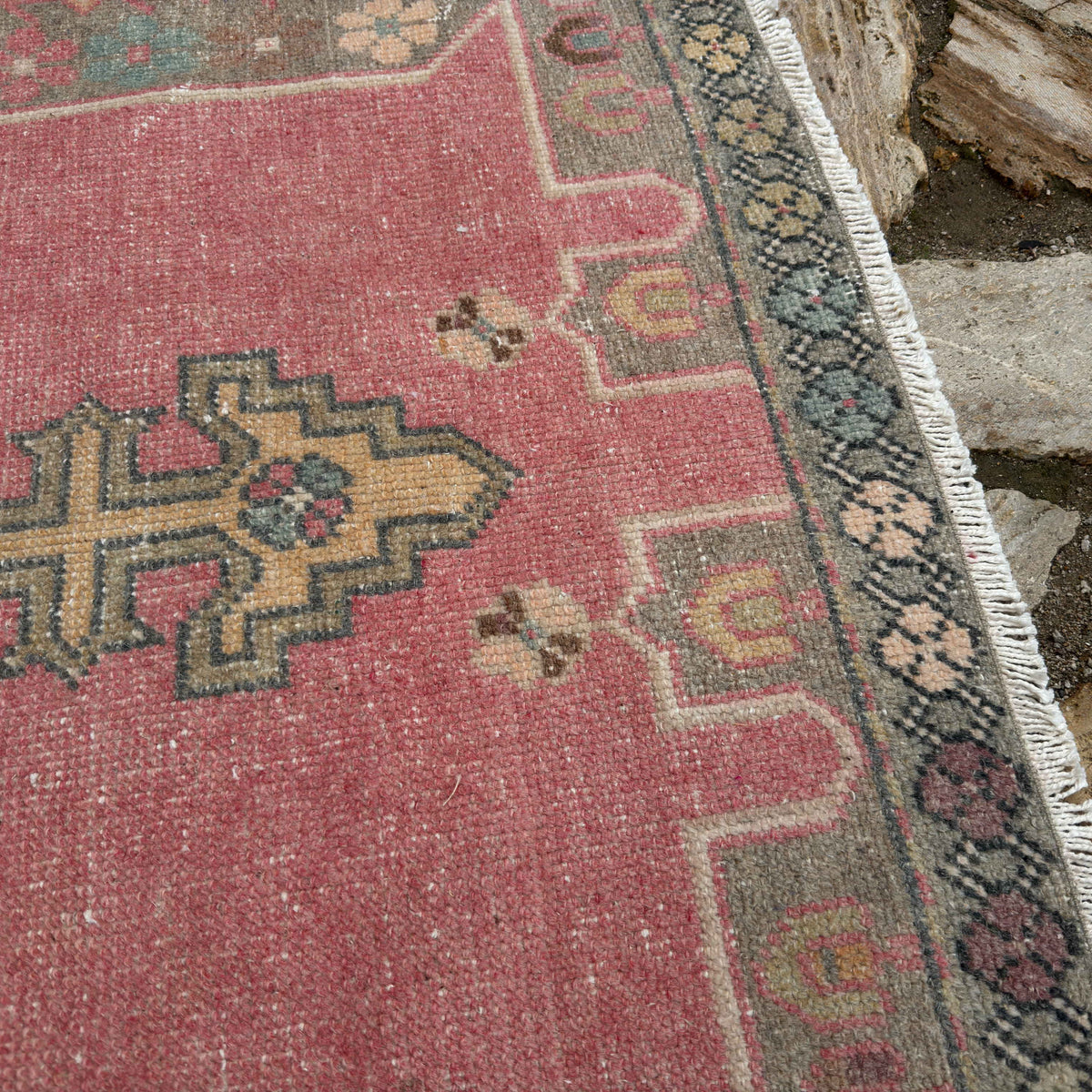 Close-up of the pale pink Turkish traditional vintage rug showing traditional details, hand-knotted weave, wool and cotton and low pile.