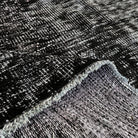 Close-up of the gray turkish overdyed rug showing overdyed details, hand-knotted weave, wool and cotton and low pile.