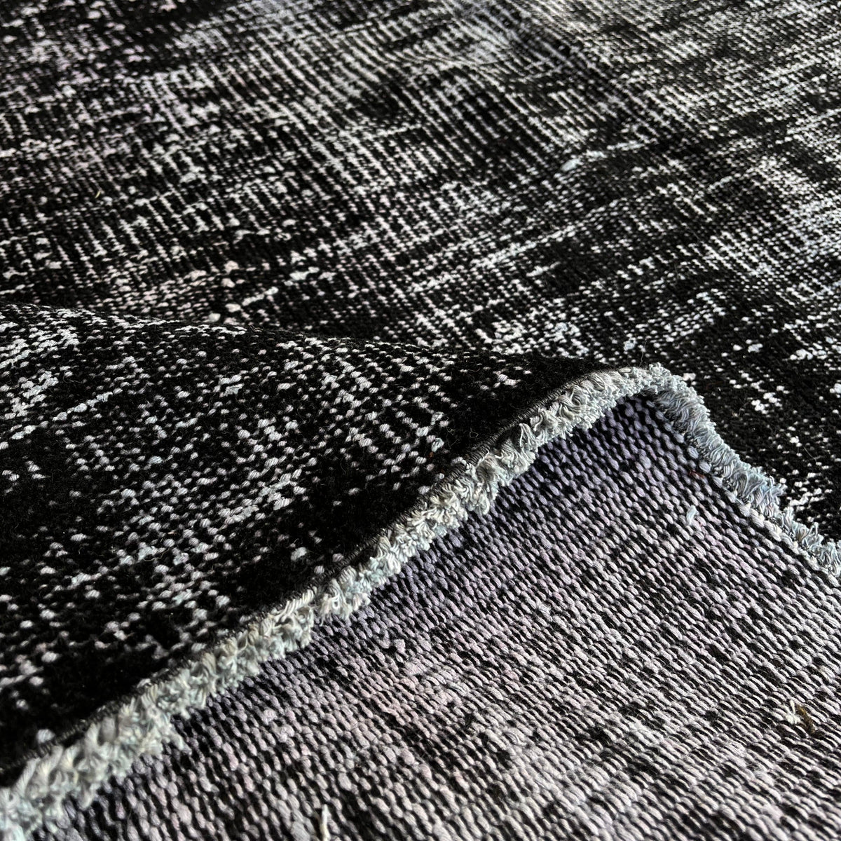 Close-up of the gray turkish overdyed rug showing overdyed details, hand-knotted weave, wool and cotton and low pile.