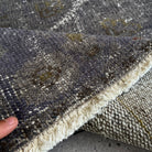 Close-up of the black turkish overdyed rug showing overdyed details, hand-knotted weave, wool and cotton and low pile.