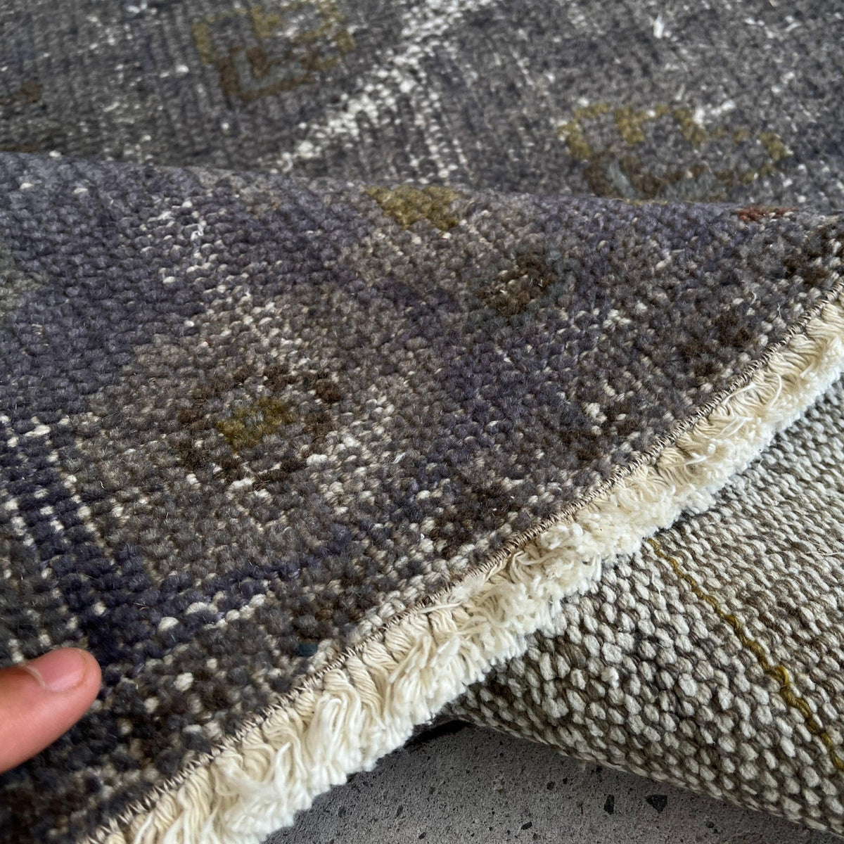 Close-up of the black turkish overdyed rug showing overdyed details, hand-knotted weave, wool and cotton and low pile.