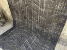 Black 6' x 9' turkish overdyed rug in wool and cotton, shown on the floor.