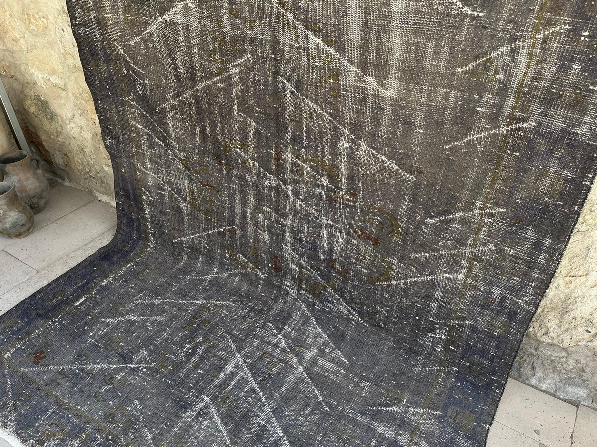 Black 6' x 9' turkish overdyed rug in wool and cotton, shown on the floor.