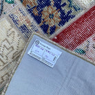 Close-up of the red turkish patchwork rug showing patchwork details, hand-knotted weave, wool and cotton and low pile.