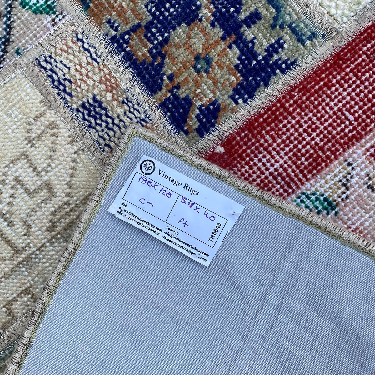Close-up of the red turkish patchwork rug showing patchwork details, hand-knotted weave, wool and cotton and low pile.
