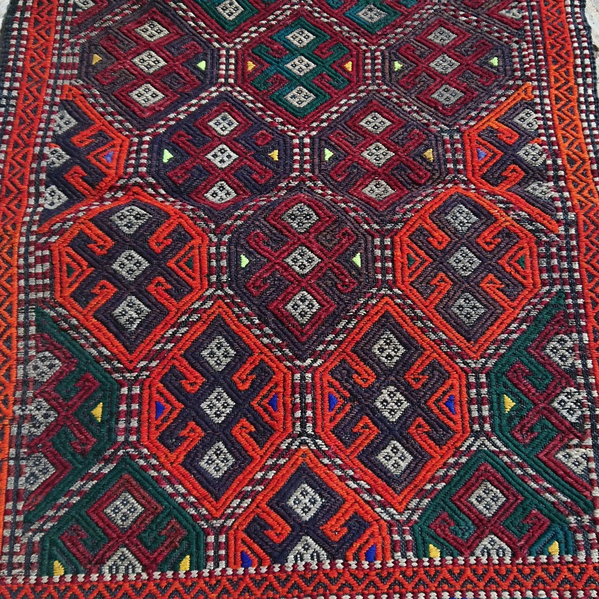Close-up of the orange turkish rug showing traditional details, flatweave construction, wool and cotton and low pile.