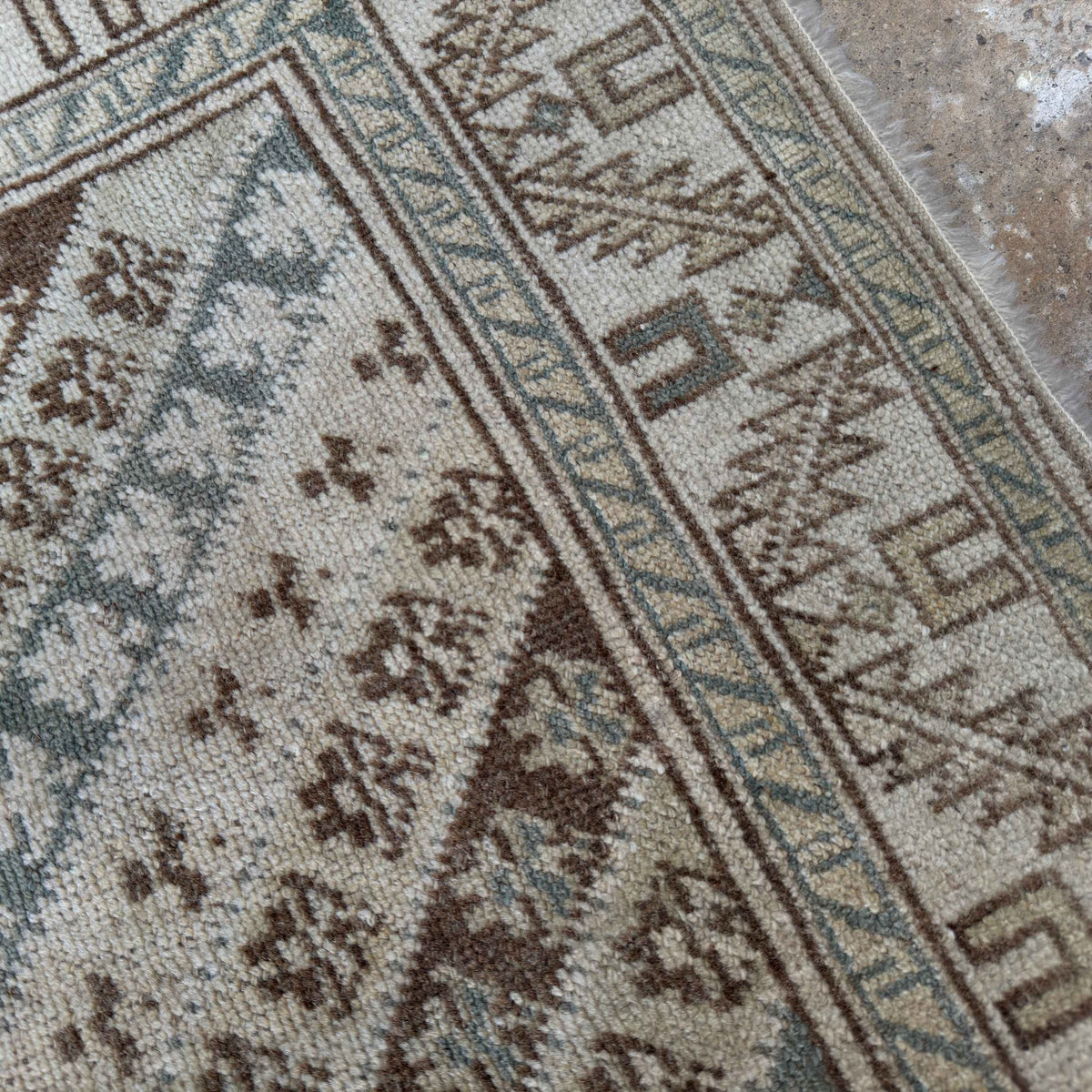 Close-up of the pale blue turkish rug showing striped details, hand-knotted weave, wool and cotton and low pile.