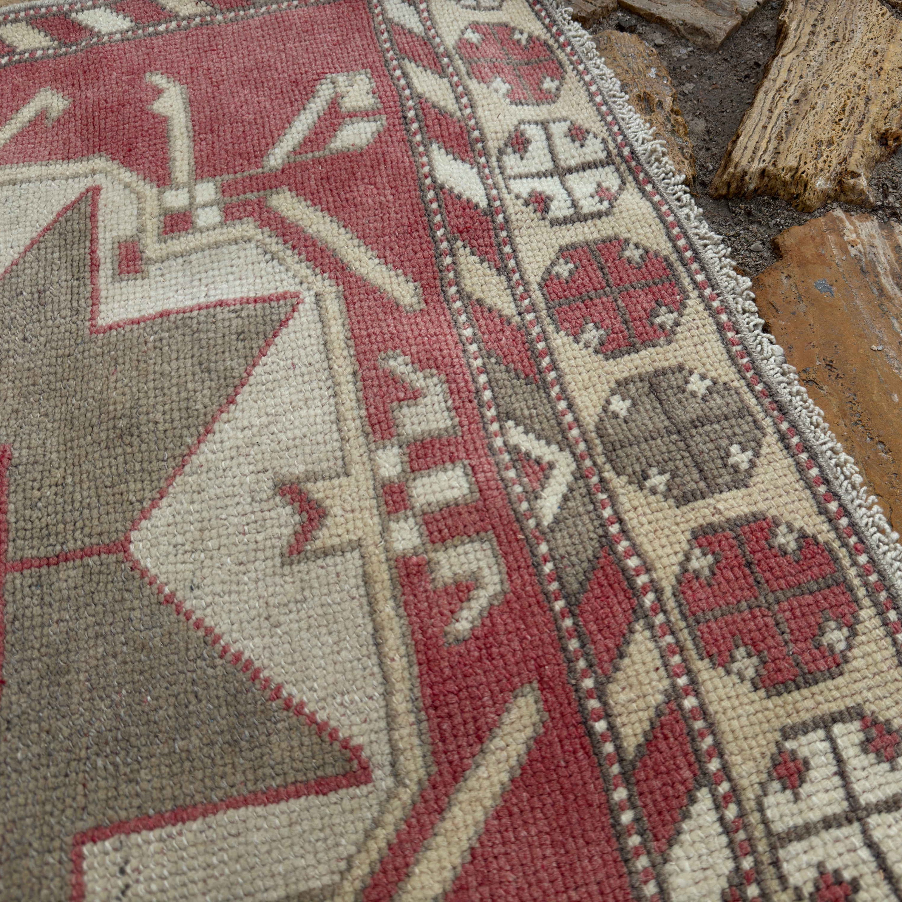 Close-up of the pale red turkish runner rug showing medallion details, hand-knotted weave, wool and cotton and low pile.