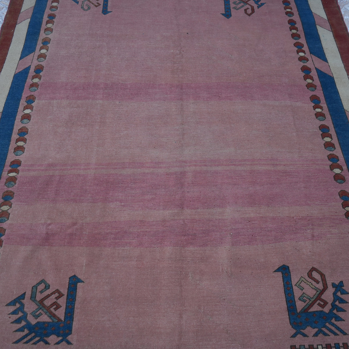 Close-up of the pink Turkish unique vintage rug showing geometric details, hand-knotted weave, wool and low pile.