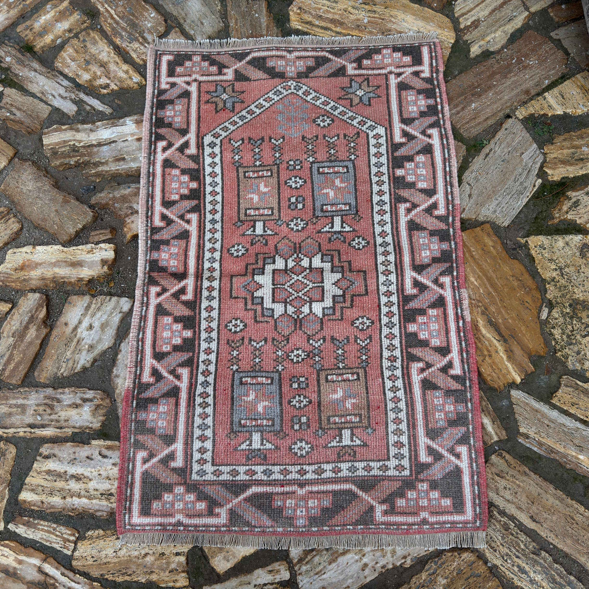 Pale Red 2' x 4' vintage Turkish anatolia rug in wool and cotton, shown on the floor.