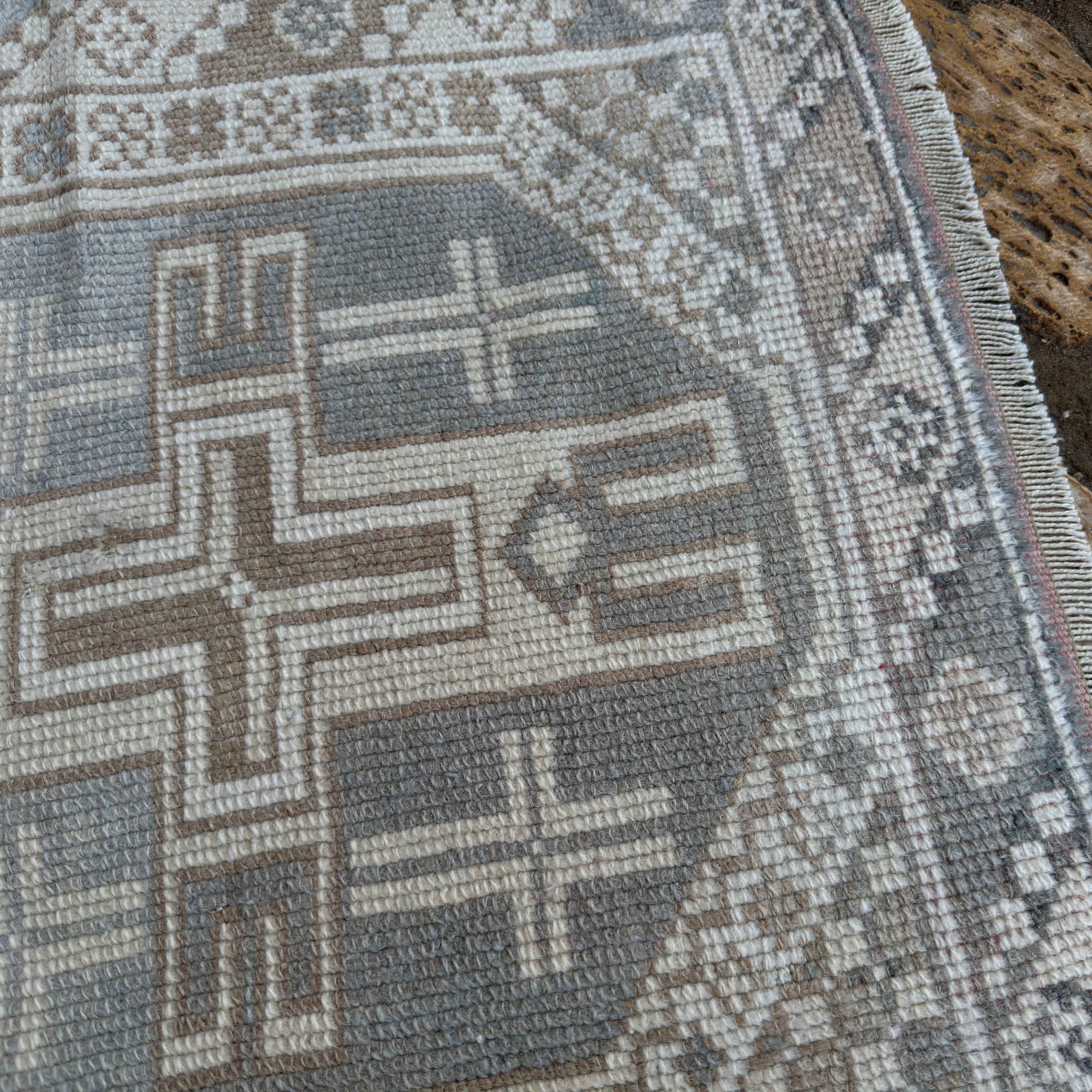Close-up of the pale blue vintage Turkish anatolian rug showing neutral details, hand-knotted weave, wool and cotton and low pile.