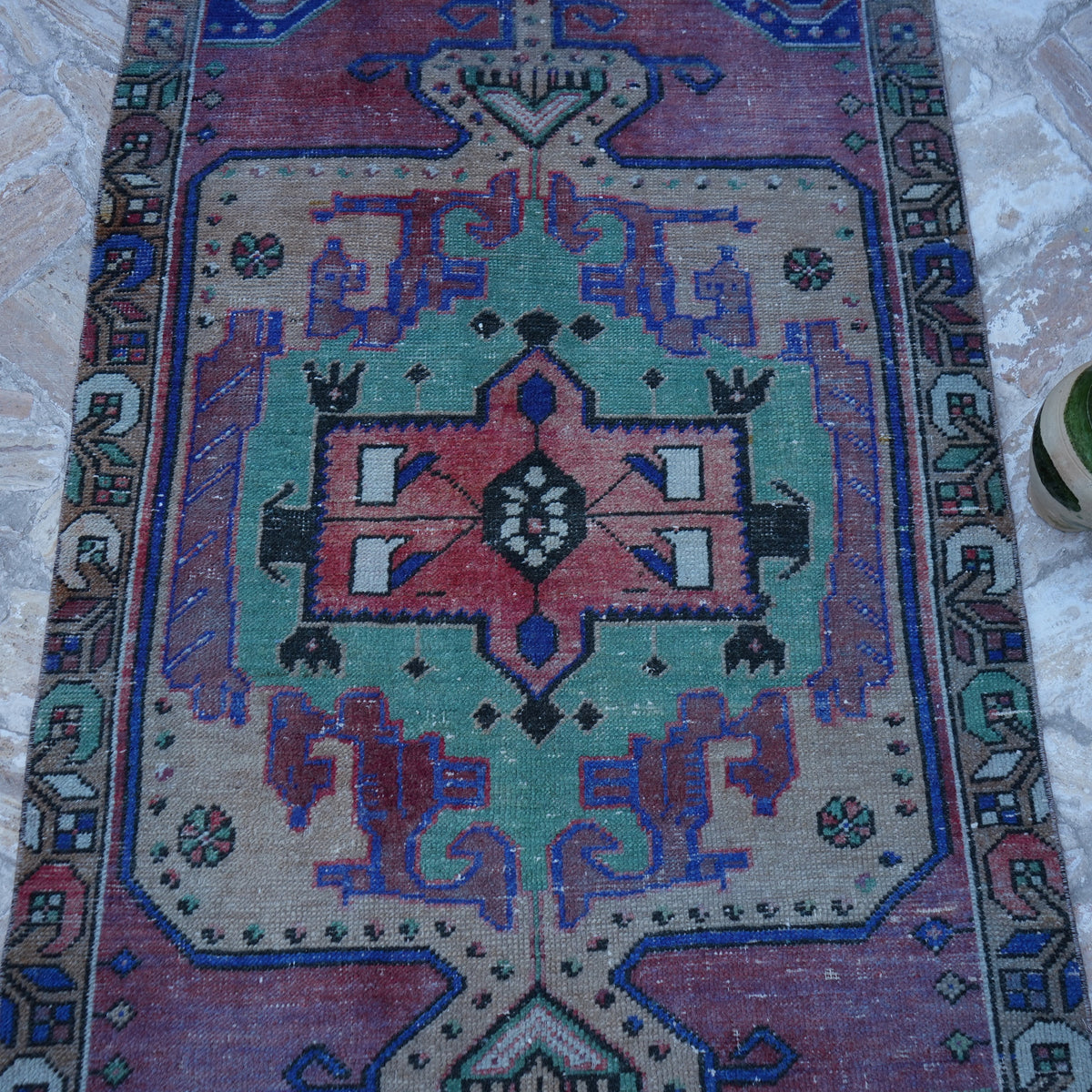 Close-up of the red vintage Turkish anatolian rug showing traditional details, hand-knotted weave, wool and cotton and low pile.
