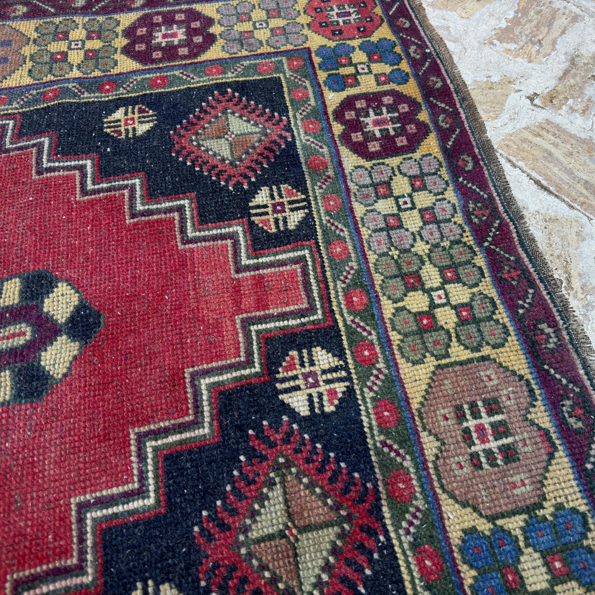 Close-up of the red vintage Turkish anatolian rug showing traditional details, hand-knotted weave, wool and cotton and low pile.