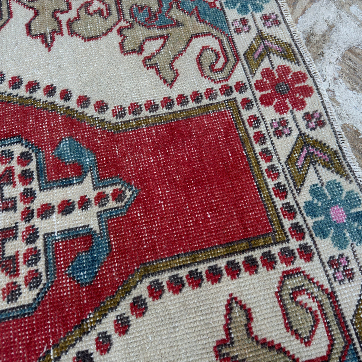 Close-up of the red vintage Turkish anatolian rug showing traditional details, hand-knotted weave, wool and cotton and low pile.