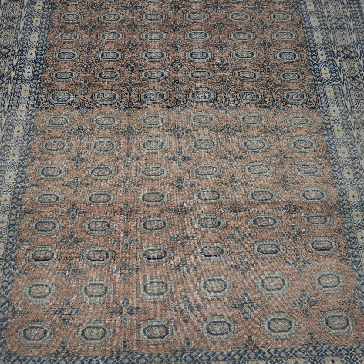 Close-up of the pale orange vintage Turkish anatolian rug showing geometric details, hand-knotted weave, wool and cotton and low pile.