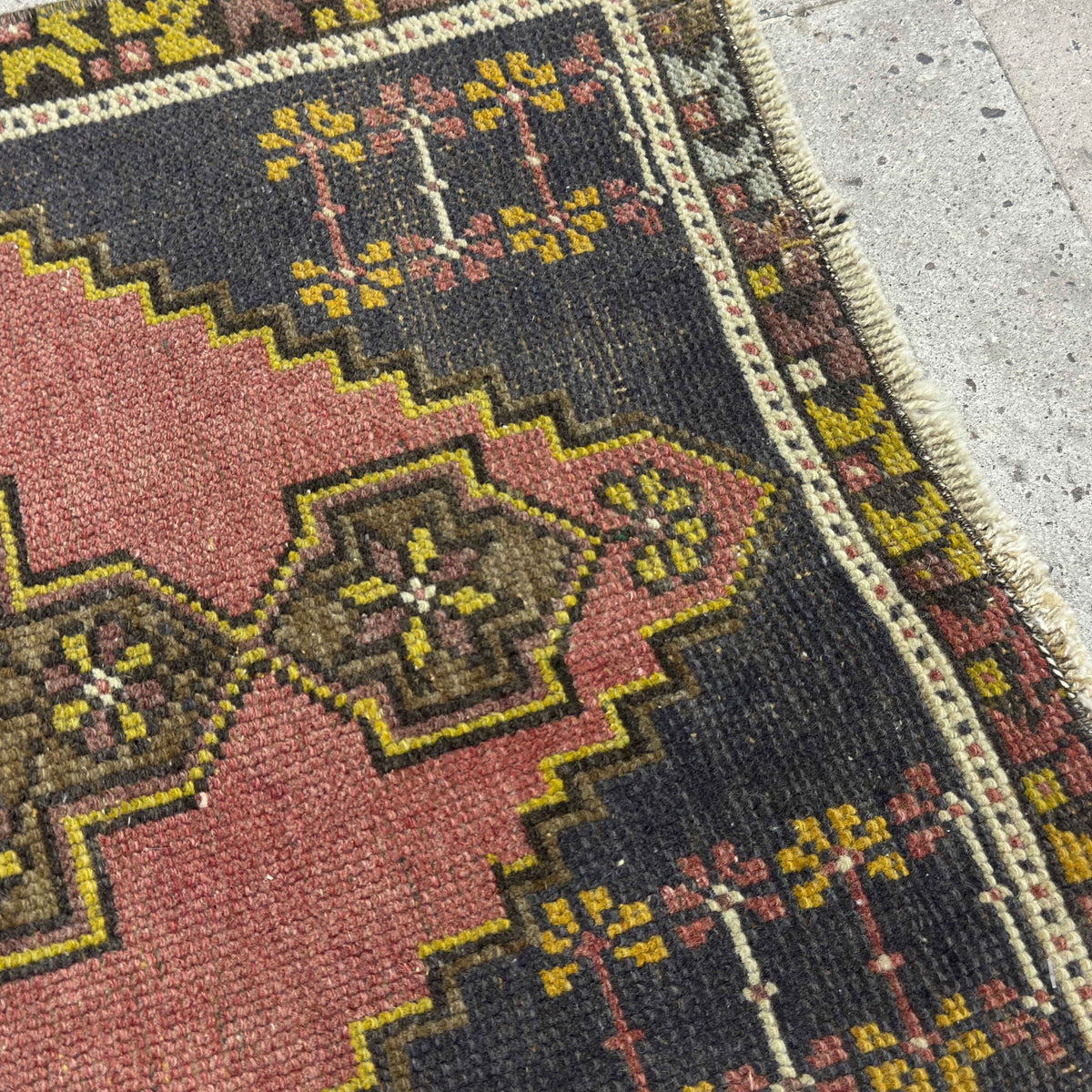 Close-up of the pink vintage Turkish area rug showing traditional details, hand-knotted weave, wool and cotton and low pile.