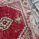 Close-up of the red vintage Turkish area rug showing geometric details, hand-knotted weave, wool and cotton and low pile.