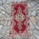 Red 2' x 5' vintage Turkish area rug in wool and cotton, shown on the floor.