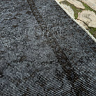 Close-up of the black vintage Turkish area rug showing overdyed details, hand-knotted weave, wool and cotton and low pile.