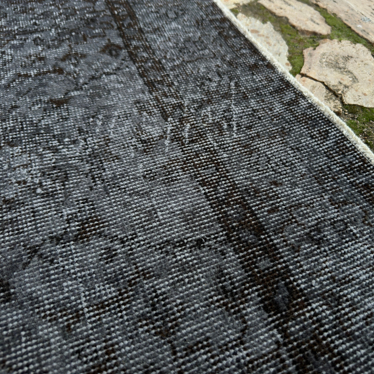 Close-up of the black vintage Turkish area rug showing overdyed details, hand-knotted weave, wool and cotton and low pile.