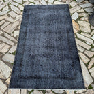 Black 4' x 6' vintage Turkish area rug in wool and cotton, shown on the floor.