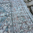 Close-up of the green vintage Turkish area rug showing floral details, hand-knotted weave, wool and cotton and low pile.