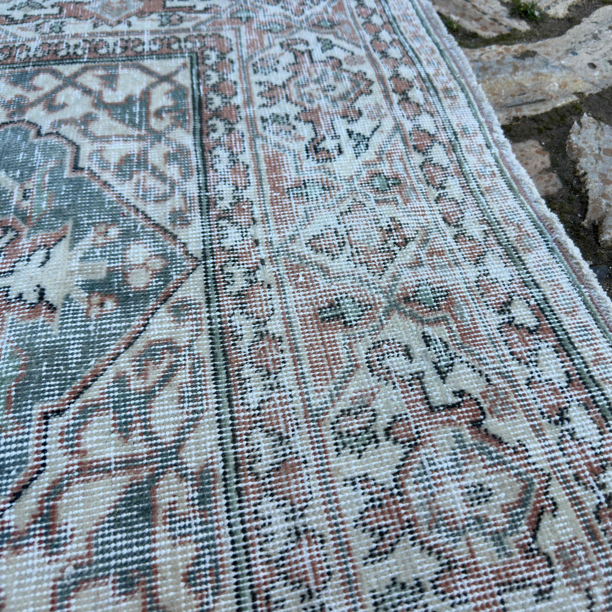 Close-up of the green vintage Turkish area rug showing floral details, hand-knotted weave, wool and cotton and low pile.