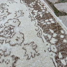 Close-up of the beige vintage Turkish area rug showing medallion details, hand-knotted weave, wool and cotton and low pile.