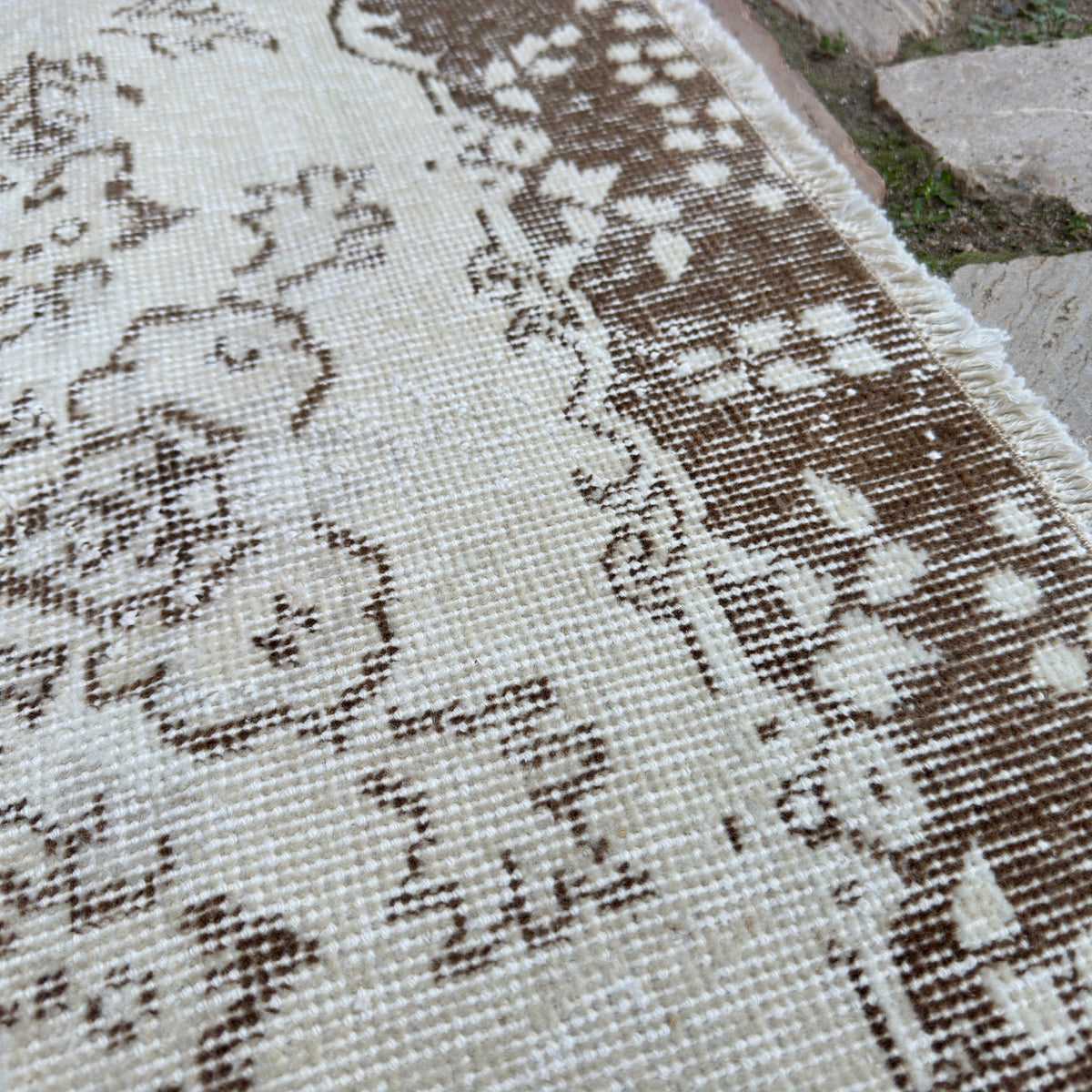 Close-up of the beige vintage Turkish area rug showing medallion details, hand-knotted weave, wool and cotton and low pile.