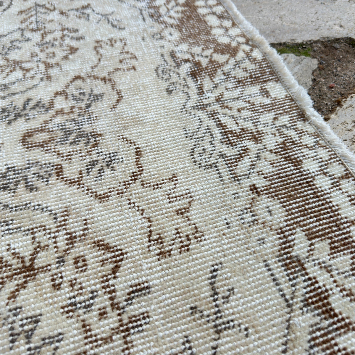 Close-up of the beige vintage Turkish area rug showing medallion details, hand-knotted weave, wool and cotton and low pile.