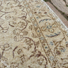 Close-up of the beige vintage Turkish area rug showing floral details, hand-knotted weave, wool and cotton and low pile.