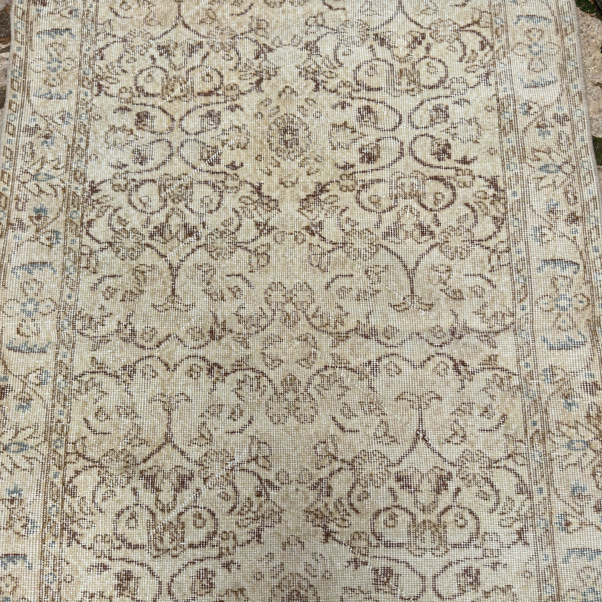 1970s beige vintage Turkish area rug with floral design, hand-knotted weave and low pile.