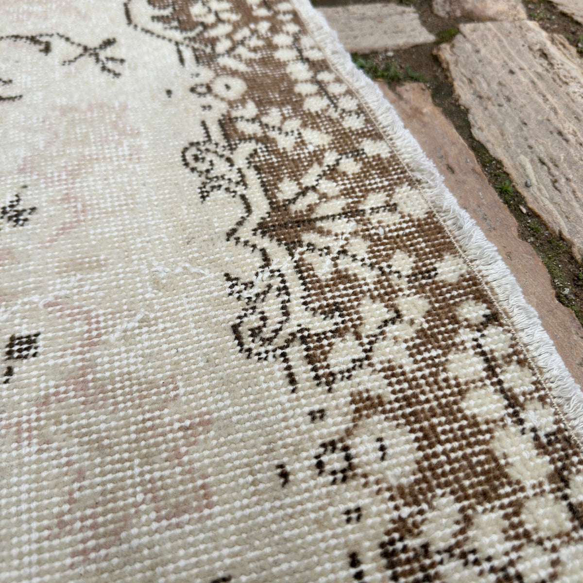 Close-up of the brown vintage Turkish area rug showing medallion details, hand-knotted weave, wool and cotton and low pile.