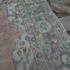 Close-up of the pale red vintage Turkish area rug showing traditional details, hand-knotted weave, wool and cotton and low pile.