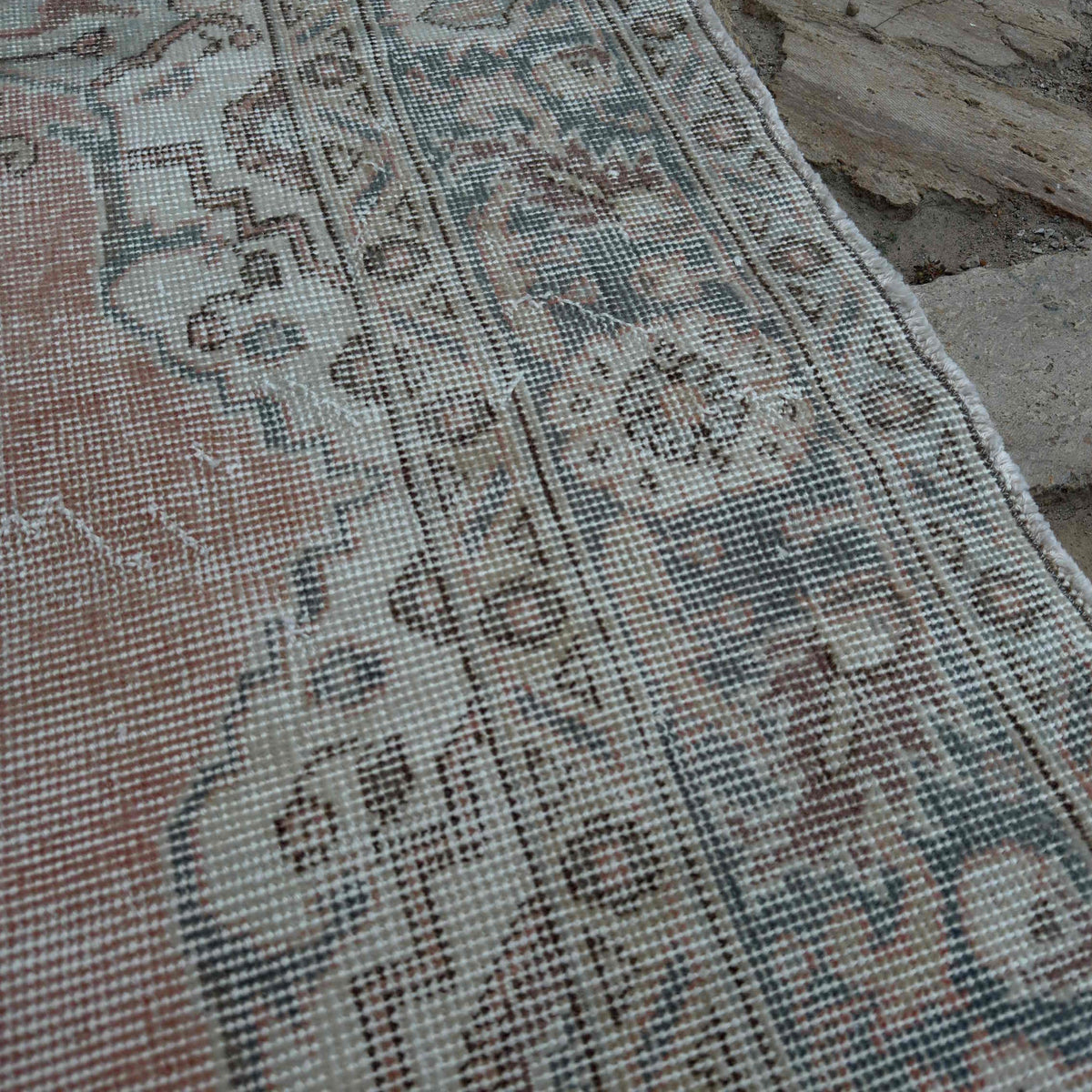 Close-up of the pale red vintage Turkish area rug showing traditional details, hand-knotted weave, wool and cotton and low pile.