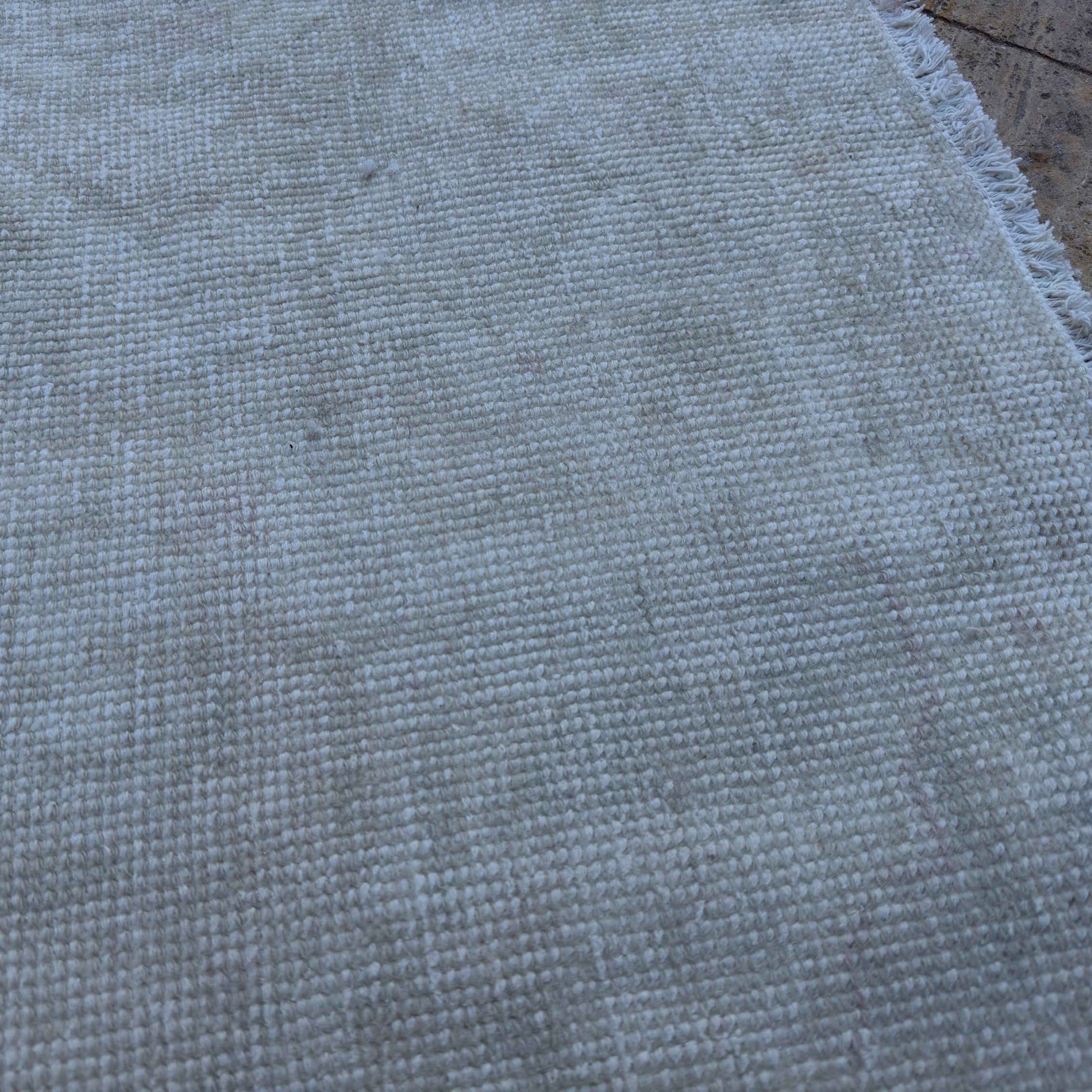 Close-up of the beige vintage Turkish area rug showing neutral details, hand-knotted weave, wool and cotton and low pile.