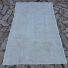 Beige 5' x 7' vintage Turkish area rug in wool and cotton, shown on the floor.