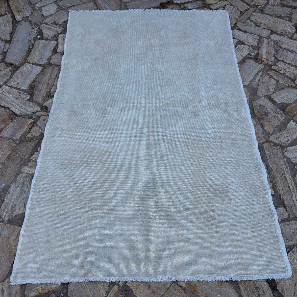 Beige 5' x 7' vintage Turkish area rug in wool and cotton, shown on the floor.