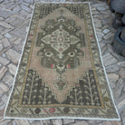 Pink 5' x 9' vintage Turkish area rug in wool and cotton, shown on the floor.